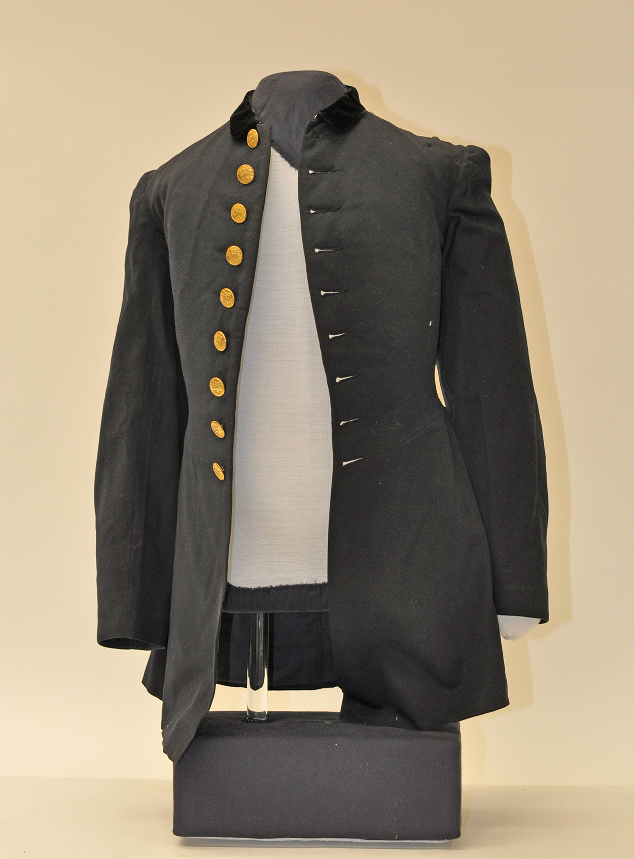 A dark blue  coat with gold buttons displayed on a mannequin